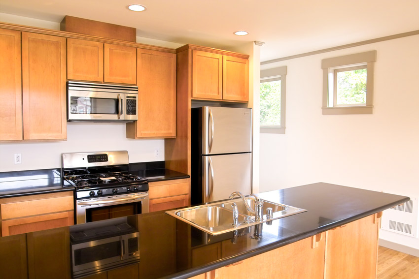 Kitchen with black countertop. small window, oven and refrigerator