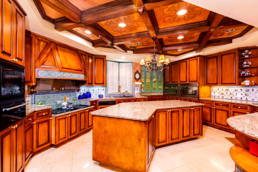 Kitchen with cherry wood cabinets, island, backsplash, coffered ceiling, and lighting fixtures