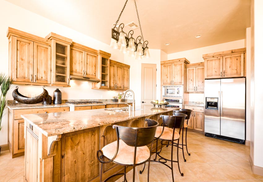 Kitchen with natural oak cabinets, countertops, island, chairs, and pendant lights