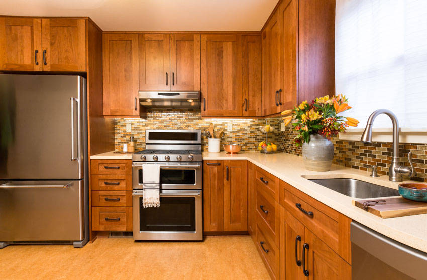 Kitchen with partial overlay recessed cabinets, tile backsplash, countertop, wood floor, oven, refrigerator, sink, faucet, and window