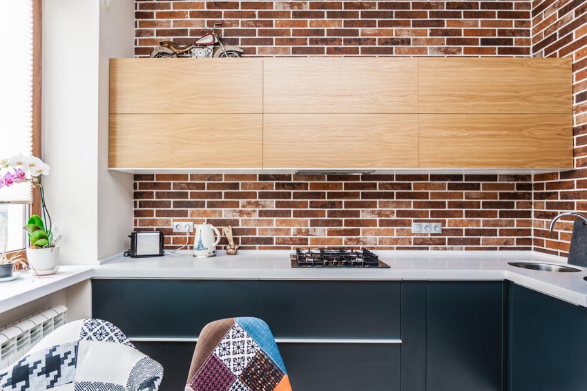 Kitchen with peel and stick brick backsplash, cabinets, window, countertop, and stove