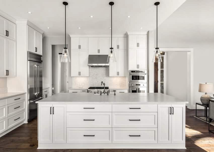 Kitchen with pendant lights, hardwood floors, and white cabinets with black hardware