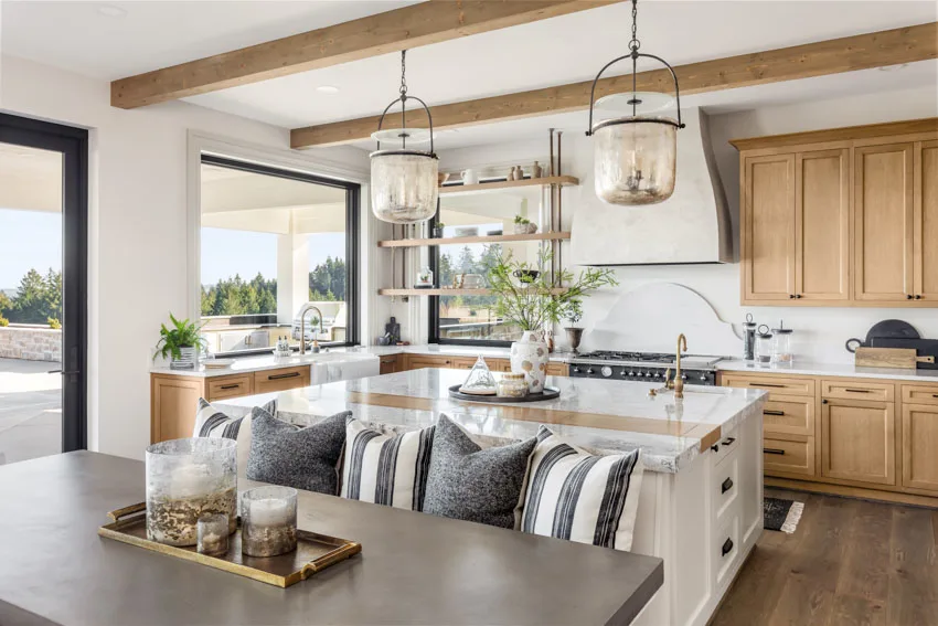 Kitchen with poplar cabinets, doors, island, countertops, dining table, pendant lights, wood ceiling beams, backsplash, shelves, and windows