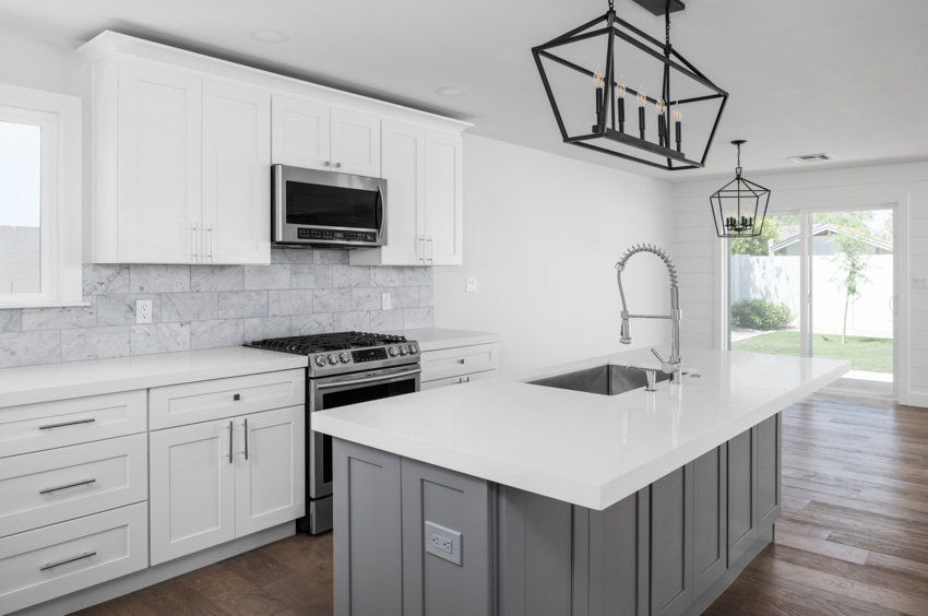 An all white kitchen with black candle style pendants