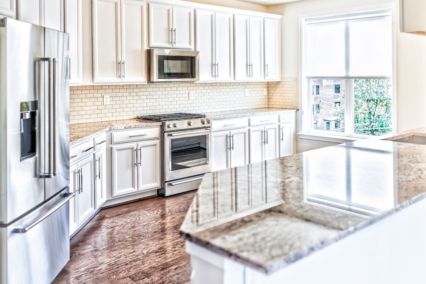 Kitchen with recessed cabinets, countertop, island, oven, stove, refrigerator, and glass door