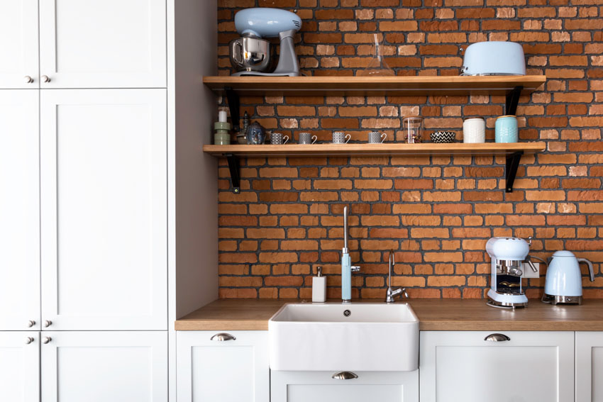 Kitchen with brick backsplash, sink, floating shelves, and cabinets