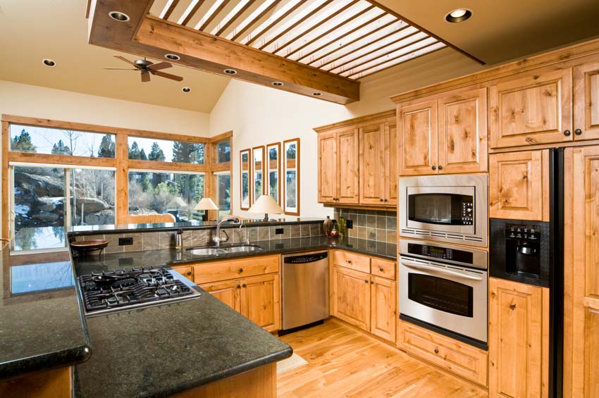 Kitchen with stove, countertops, oven, windows, and natural wood cabinets