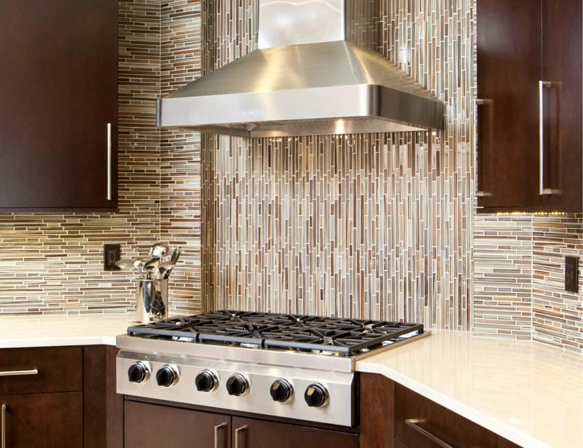 Kitchen with vertical mosaic tile and wood cabinets with chrome handles