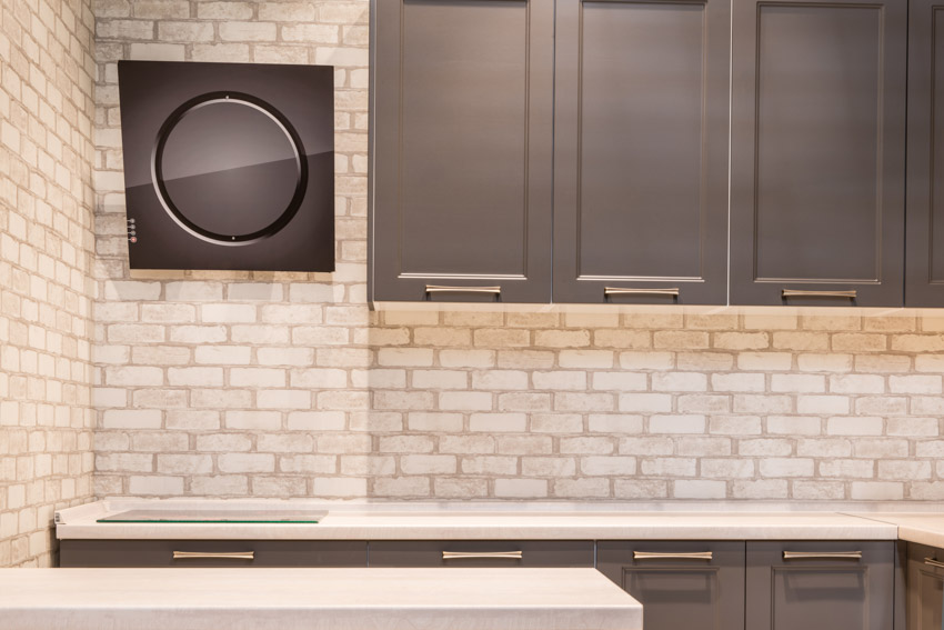 Kitchen with white brick backsplash, countertop, and cabinets