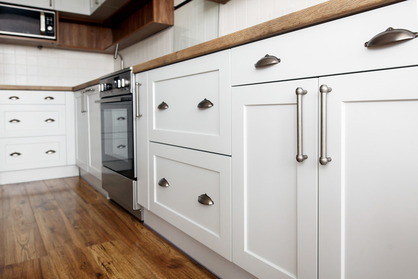 Kitchen with white shaker recessed cabinets, wood floors, stove, and countertop