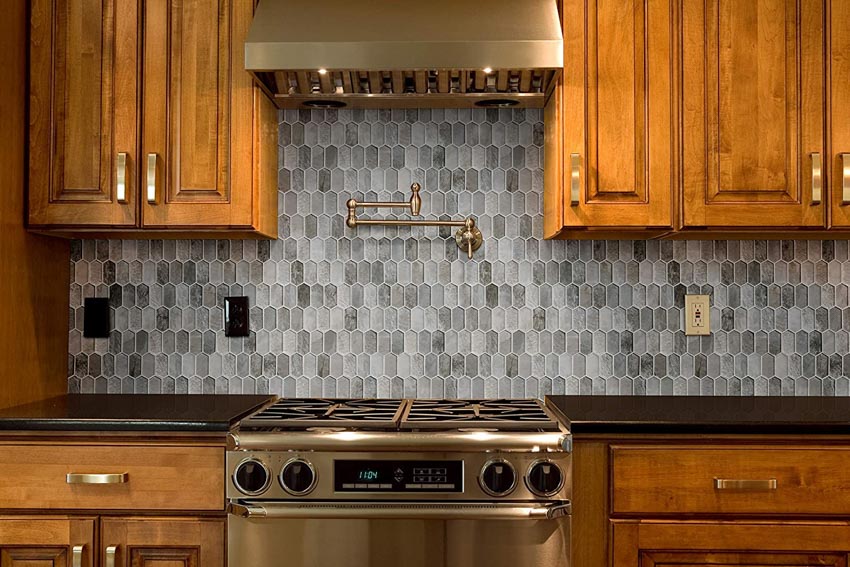 Kitchen with wood cabinets, stove, range hood, and picket tile backsplash