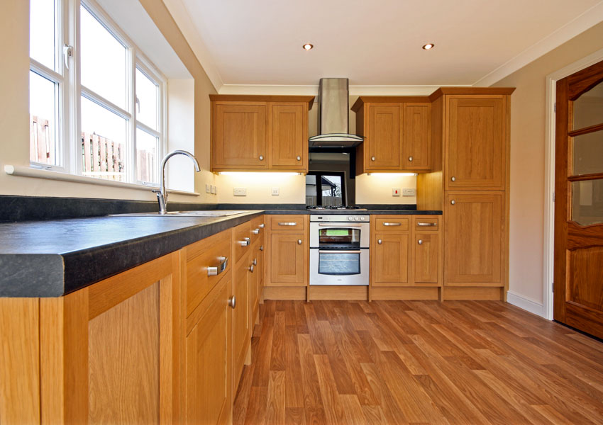 Kitchen with wooden floors, countertop, natural beech wood, cabinets, oven, range hood, and windows