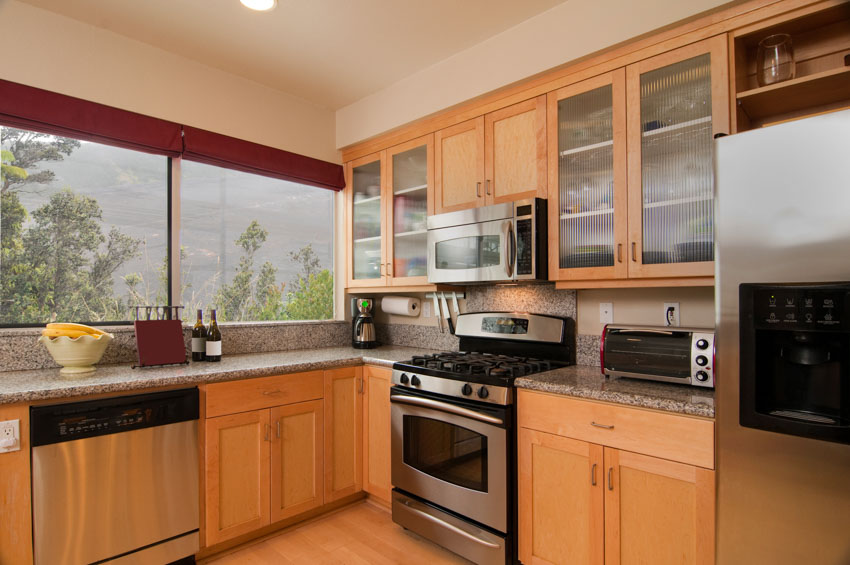 Kitchen with beech cabinets, oven, stove, windows, and granite countertop