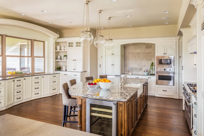 Large kitchen with white cabinets, brown granite countertops, and hardwood floors