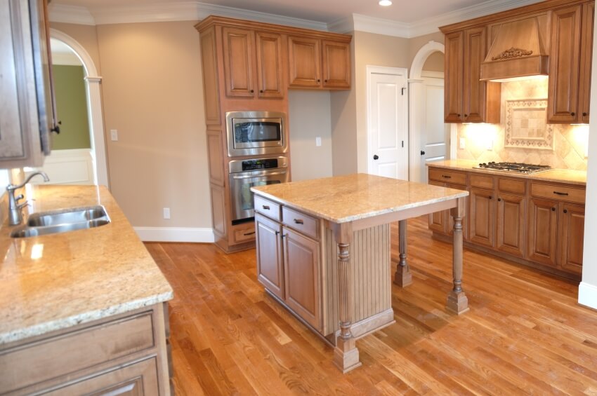 Light brown granite countertops, and wooden floor and cabinet in an empty modern kitchen