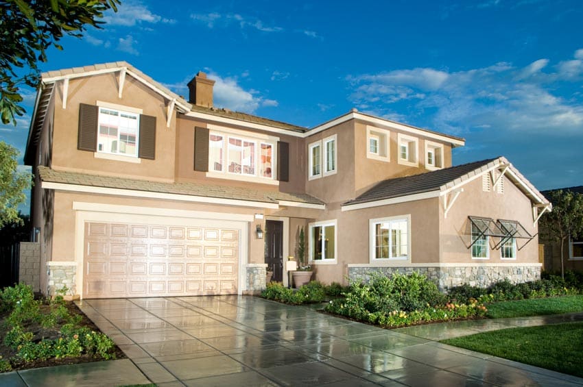 Light brown hued house with driveway, garage, and window shutters