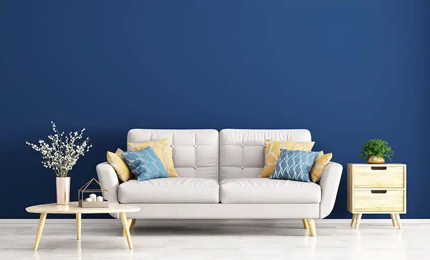 Room with dark blue walls and sofa with blue and yellow accent pillows