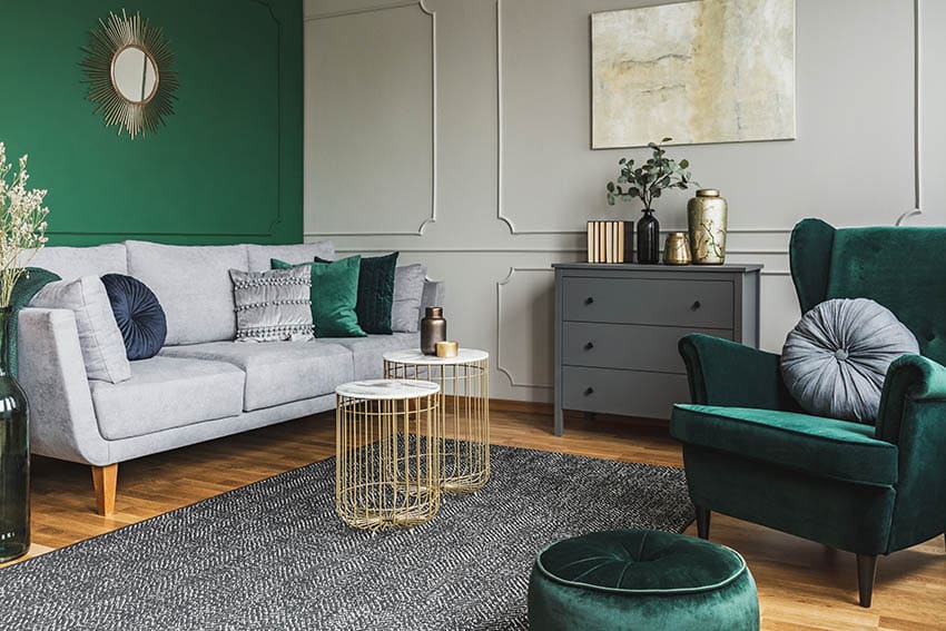 Room with green accent chair and ottoman and accent mirror on a green wall