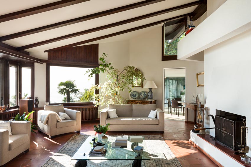 Sloping ceiling with dark wood beams, walls with decorative paneling and glass table