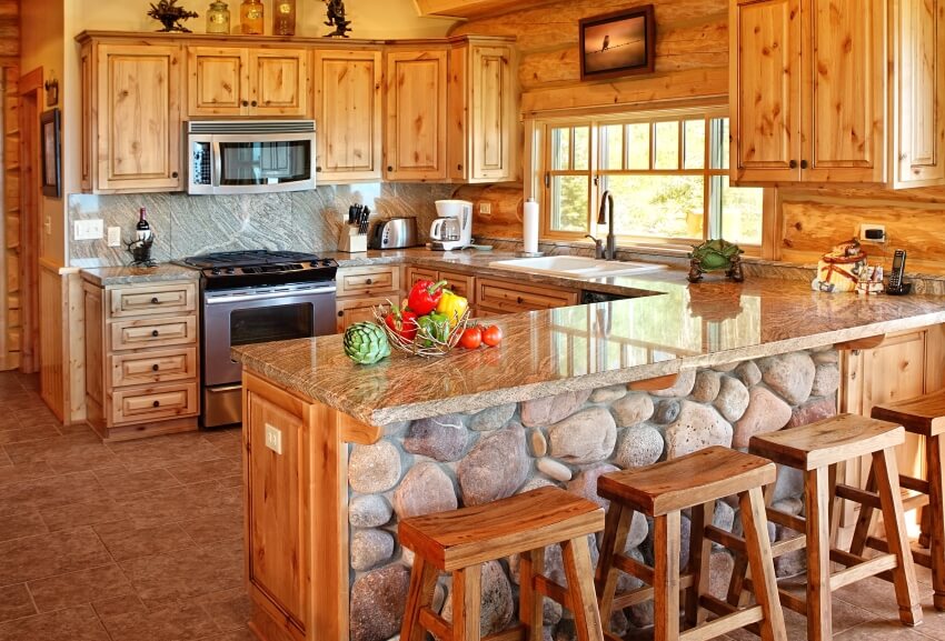 Log cabin kitchen with cedar cabinets and stone based counters with wooden stools