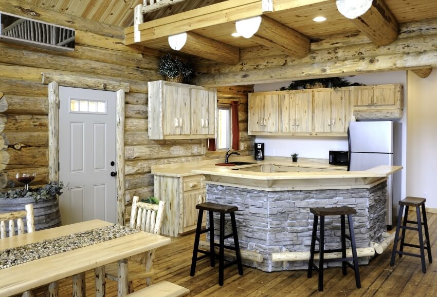 Log cabin kitchen with cedar cabinets and stone based island with bar stools