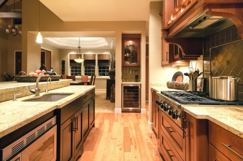 Luxurious kitchen with brown granite countertops, hardwood floors, and pendant light