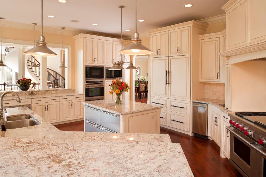 Luxury custom kitchen with stainless appliances, brown granite countertops, beige cabinets and hardwood floors