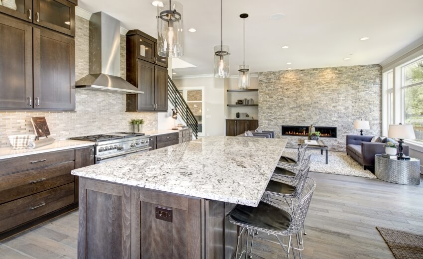 Remodeled kitchen accent with large granite island, taupe tile backsplash, and a fireplace sitting area
