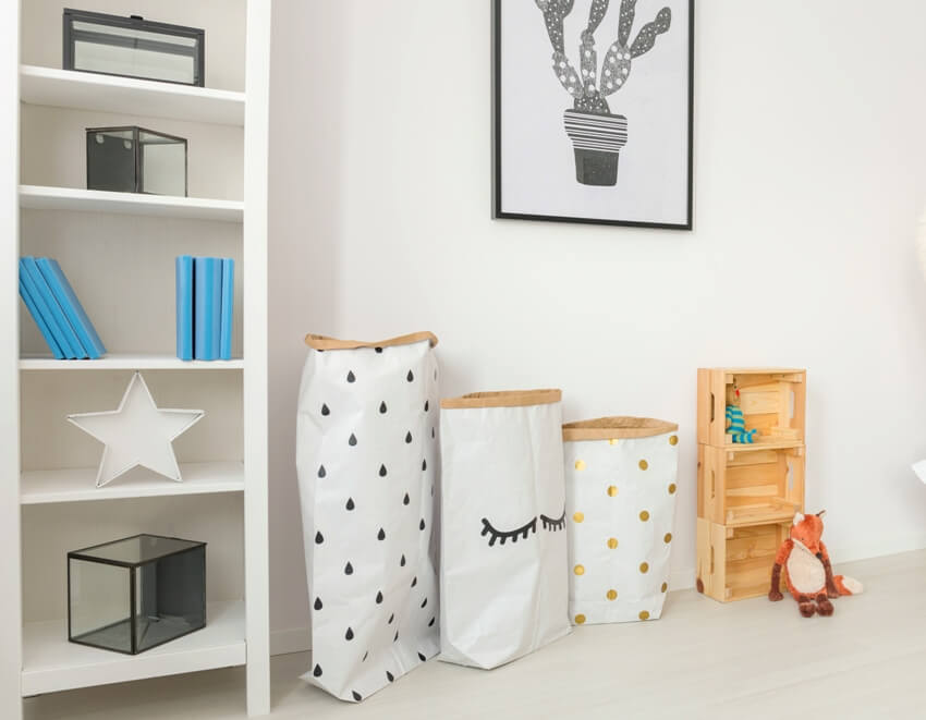 Modern baby nursery with neutral accents and minimalistic accessories including clothing hamper