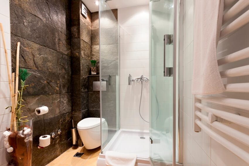 Bathroom with natural stone accentwall, above toilet shelving and shower