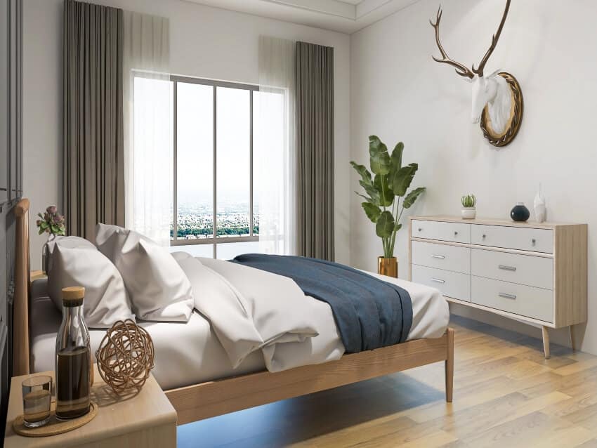 Modern bedroom with a large bed, panoramic window, and dresser with organized decors on top