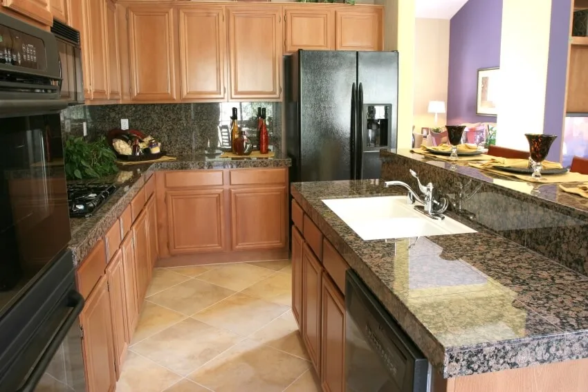 Modern kitchen with black appliances, and baltic brown granite countertops and backsplash