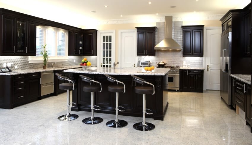 Modern kitchen with granite floors and countertops, bar stools, and dark brown cabinets