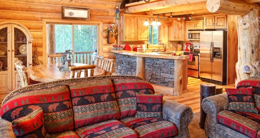 Modern log cabin with colorful couch, rustic cedar kitchen cabinets, and stone based kitchen counter