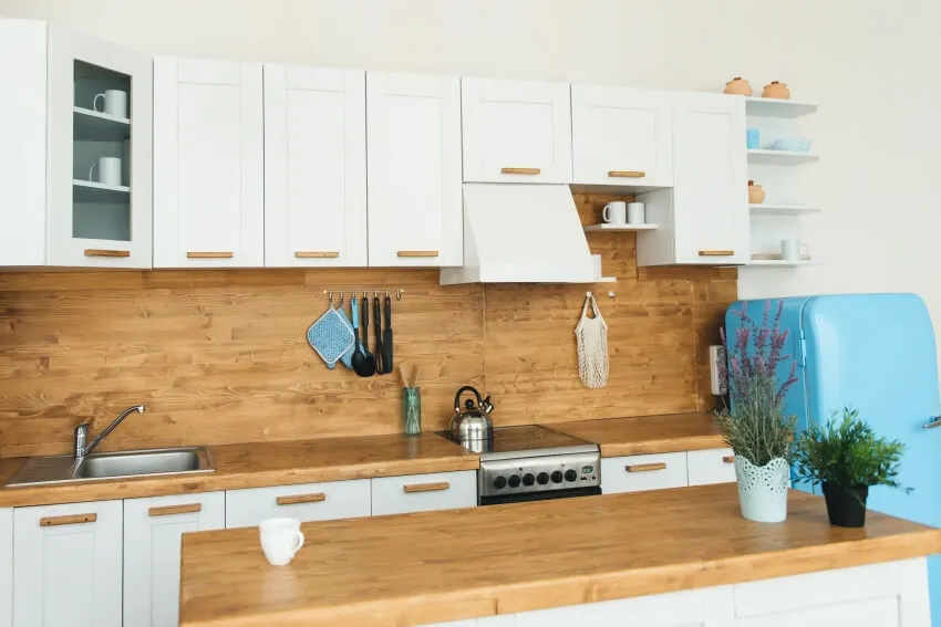 Backsplash made of faux wood, cabinets, and a small blue refrigerator
