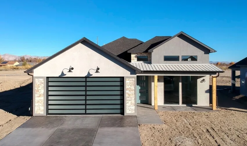 Newly constructed home with roof shingle and black garage doors with frosted glass