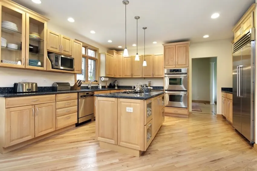 Oak wood cabinets, black granite countertops, and stainless steel appliances in an arts and crafts kitchen
