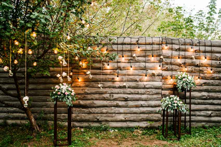 Outdoor area with fence hanging lights and small tree