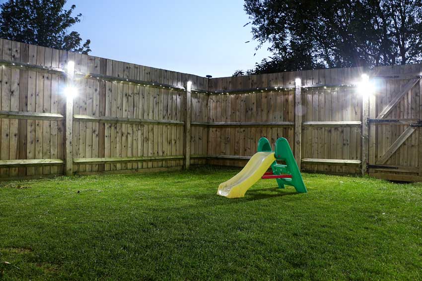 Outdoor area with kiddie slide, fence, and downlighting fixtures