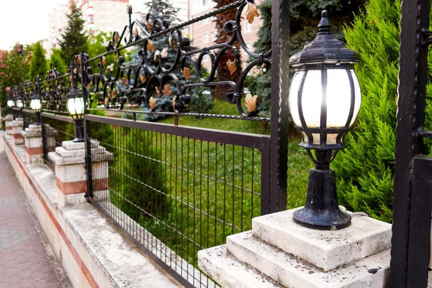 Outdoor area with metal fence, hedge plants, and fence lights