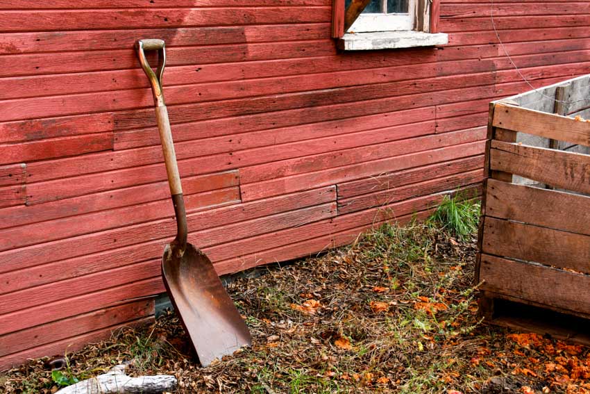 Outdoor area with shovel and red wood siding