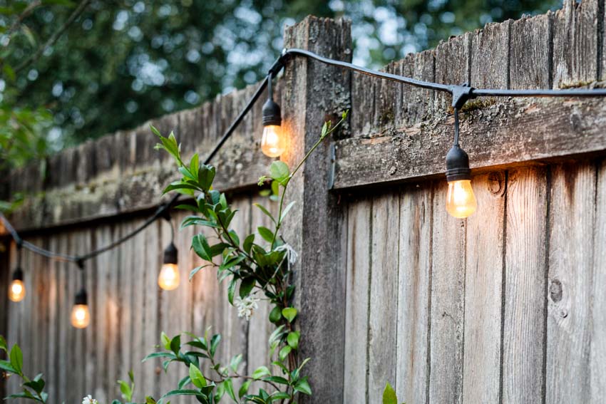 Outdoor area with string lights on a fence