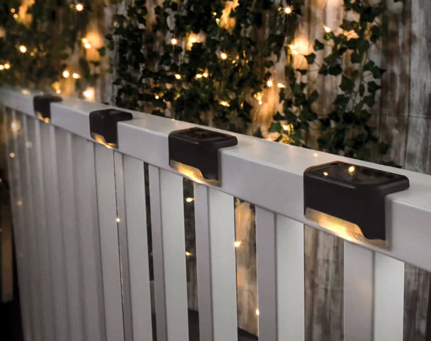 Outdoor area with white fence, rail lights, and hanging vines