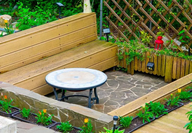 Outdoor patio surrounded with plants and composite boards benches around the table