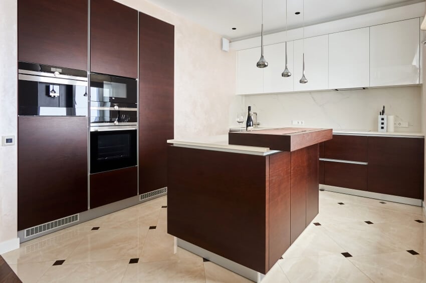 Pendant lights over island, tile floors and brown aluminum cabinets in a clean kitchen