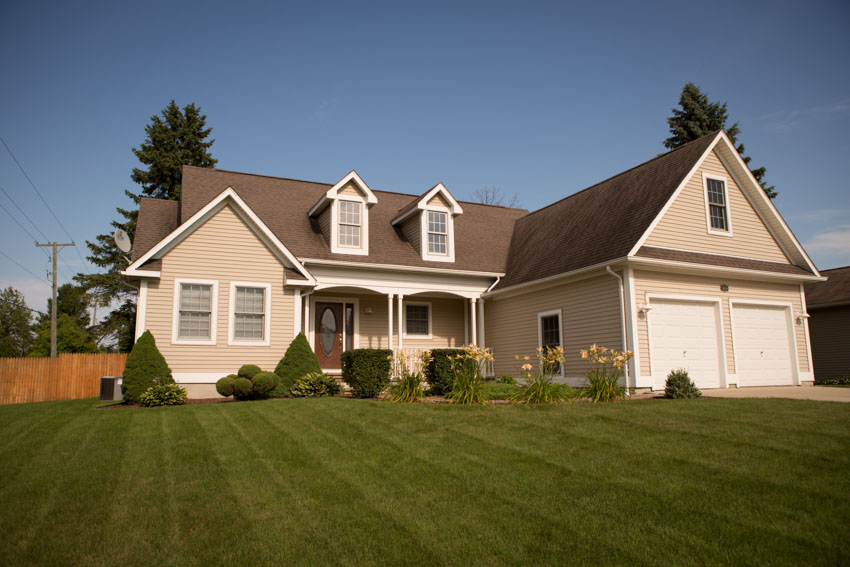 House with dormers, front porch, and hedge plants