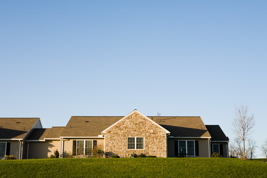 House with stone cladding, windows with shutters, and shingles roof