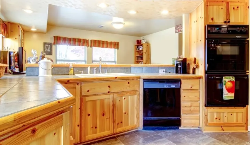 Kitchen with tile floors, windows with curtains and grey backsplash