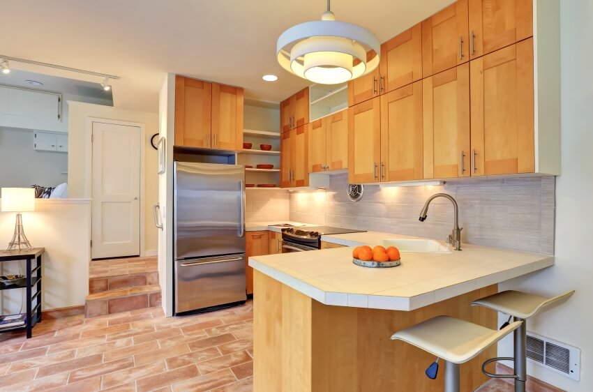 Small kitchen with brick tile floor, birch cabinet, and a stylish pendant light
