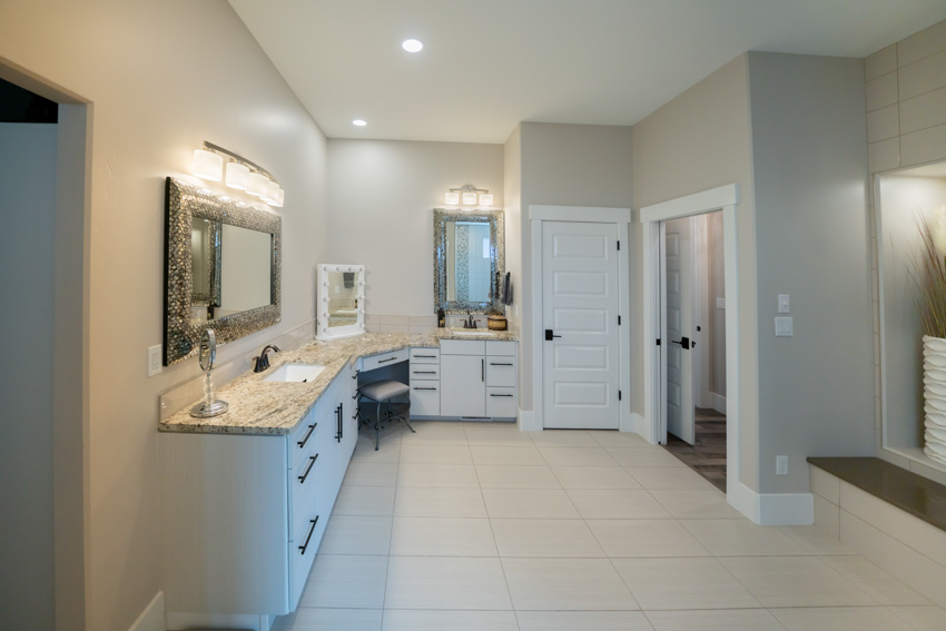 Spacious vanity area with countertop, sink, mirror, ceiling light, and unglazed porcelain tile flooring